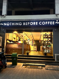 Nothing Before Coffee cafe storefront at night with glowing sign and warm interior lighting