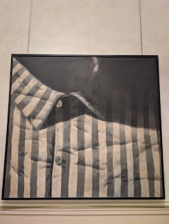 Framed monochrome painting of a folded striped dress shirt displayed on a gallery wall
