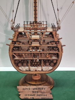 Detailed wooden scale model of HMS Victory ship showing cross-section with cannon decks and rigging