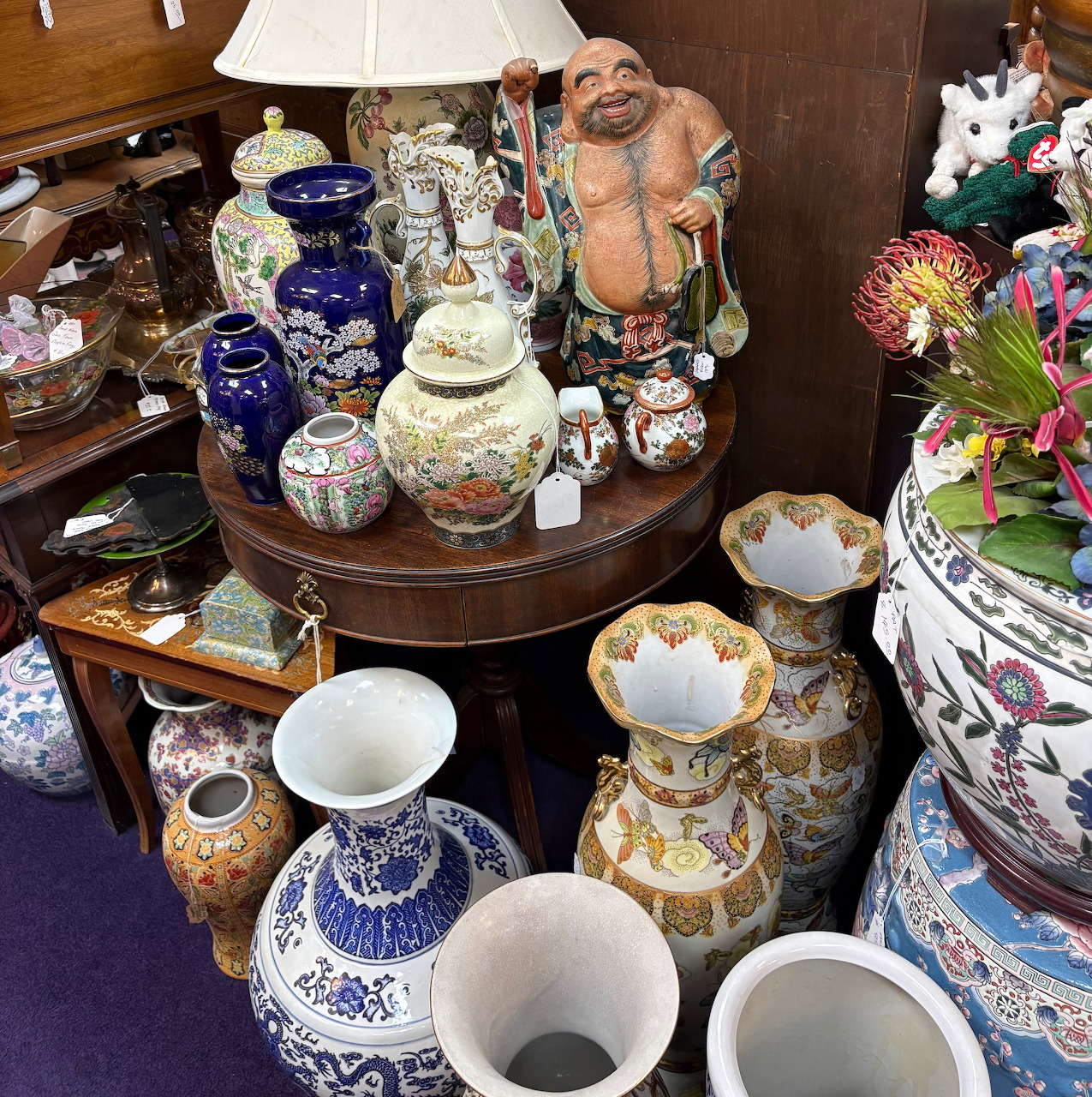 Assorted vintage pottery, vases, and ceramic figurines displayed on dark wooden shelves
