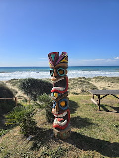 Colorful totem on sandy dunes by the ocean under a clear blue sky