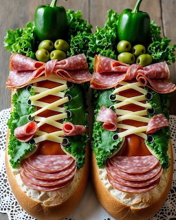 Two sandwiches crafted to look like sneakers with salami, cheese laces, lettuce, olives, and bell pepper tops