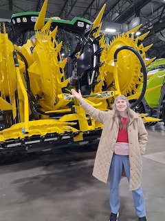 Woman standing before large yellow industrial machinery with visible gears in warehouse