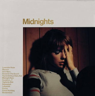 Album cover of Taylor Swift posing in a striped sweater with Midnights text above
