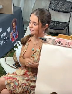 Young woman in floral dress sitting at outdoor caricature artist booth