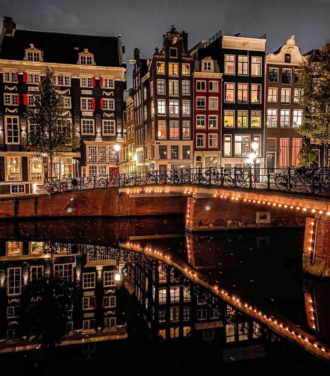Amsterdam canal at night with illuminated Dutch houses reflected in the water