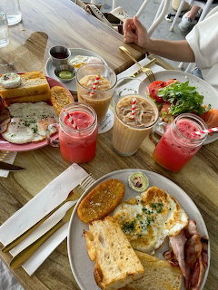 Overhead view of brunch table with toast, bacon, smoothies and salads on wooden surface