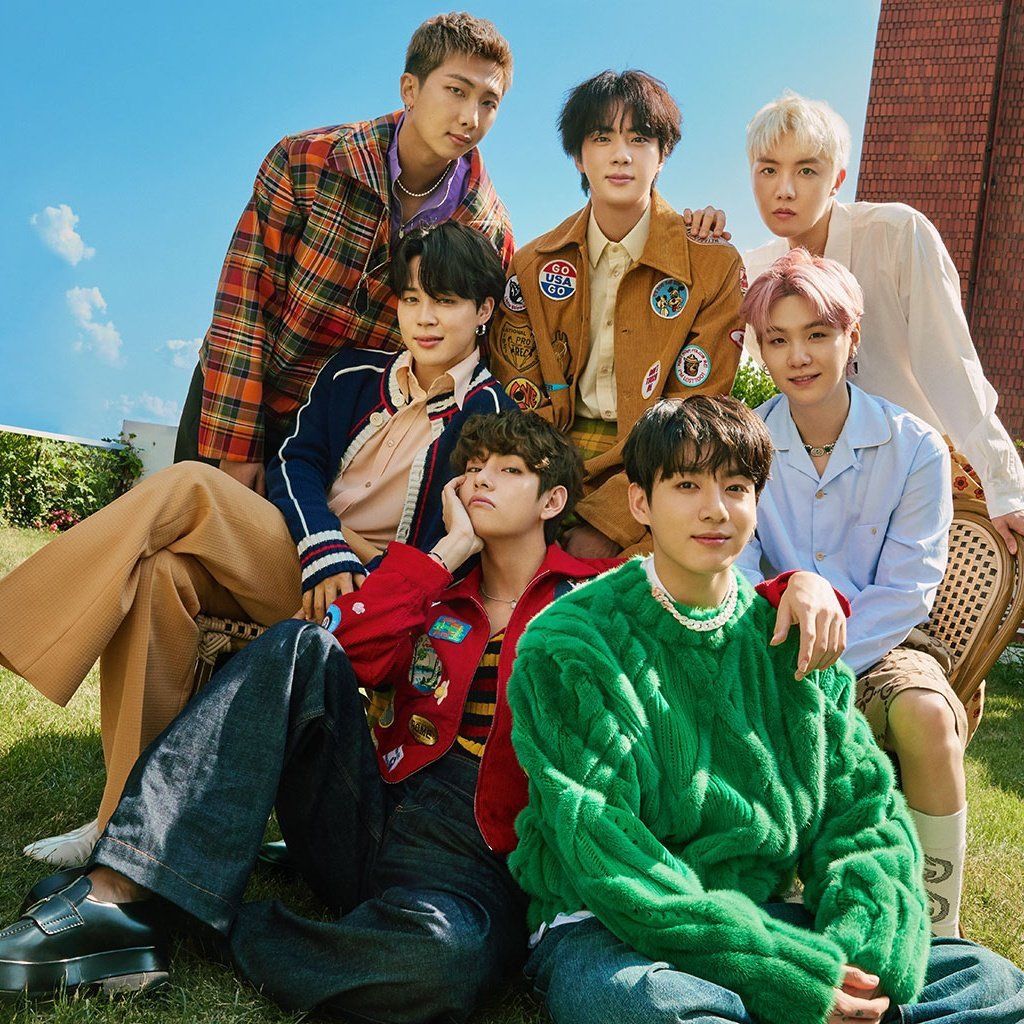 Six young men posing together outdoors in colorful clothing