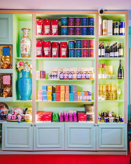 Pastel blue shelving unit filled with colorful packaged goods, bottles, and decorative products