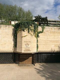 Stone memorial wall with Star of David and plaques at Hekhal Haness Synagogue, Geneva, with trees overhead