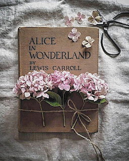 Vintage Alice in Wonderland book with pink hydrangea flowers tied with twine and antique scissors