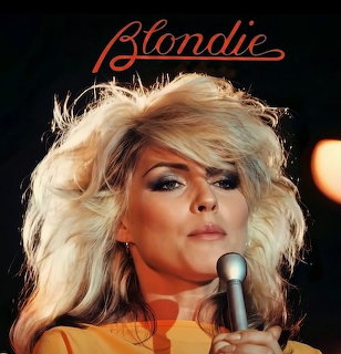 Close-up of a blonde female singer holding a microphone with Blondie text above