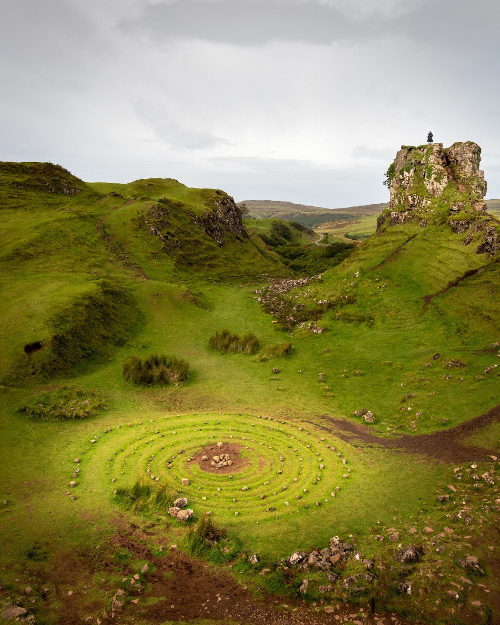 Stone circle spiral in the green valley of Fairy Glen, Isle of Skye, with a rocky pinnacle in the background