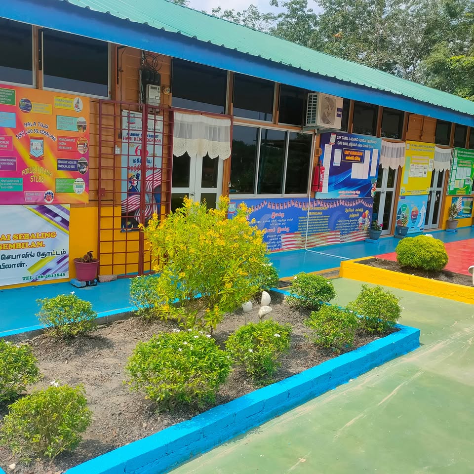 Colorful school building exterior with windows, posters, and a small garden beside a walkway