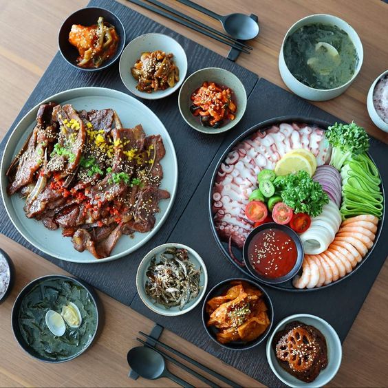 Overhead view of Japanese meal with sashimi, grilled meat, and small side dishes in bowls