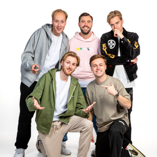 Five casually dressed young men posing together in a studio on a white background