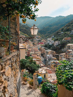 Scenic view of an Italian hillside village with terracotta roofs and a bell tower surrounded by mountains