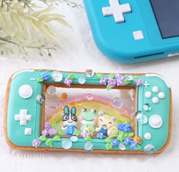 Cookie decorated as turquoise Nintendo Switch Lite handheld game console with floral icing details