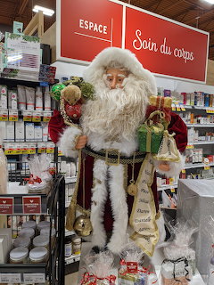 Life-size Santa Claus display in a supermarket aisle with shelves and holiday decorations