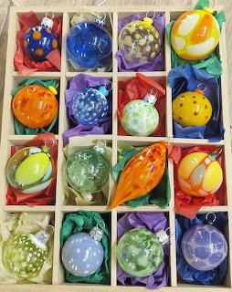 Colorful hand-painted Christmas ornaments stored in compartmented box with tissue paper
