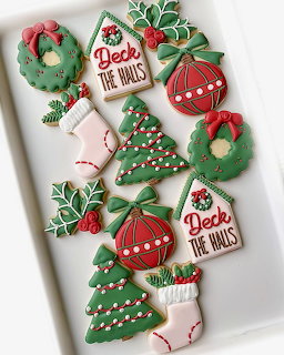 Assorted Christmas cookies with colorful icing on a white rectangular plate, featuring wreaths, trees, and ornaments