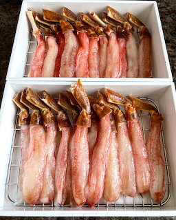 Cooked snow crab legs on white plates showing pink meat and brown shells
