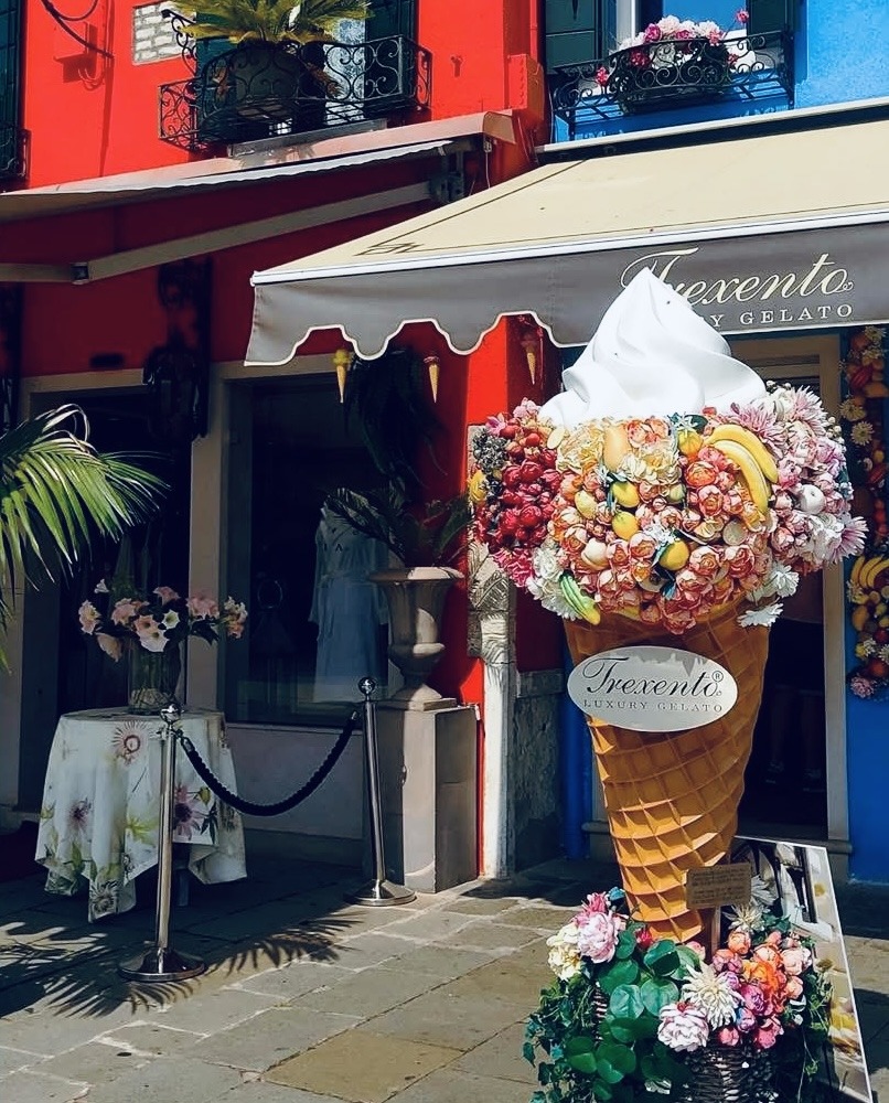 Bright ice cream shop in Burano with giant decorative cone sculpture outside colorful building