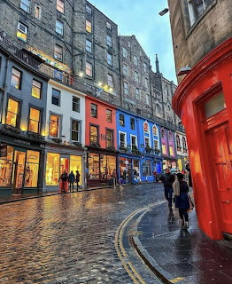 Colorful cobblestone street with historic buildings and shopfronts in Edinburgh