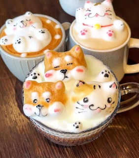 Three coffee cups with 3D foam art depicting cute cat and bear faces on a wooden surface