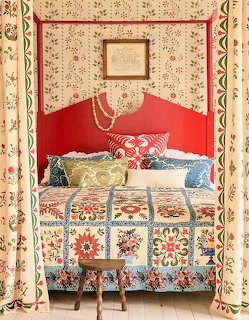 Cozy bedroom with a patchwork quilt, patterned curtains, pillows, and a red headboard