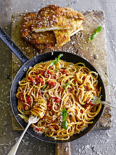 Skillet of spaghetti with tomato sauce, grated cheese, and crusted bread on a rustic table