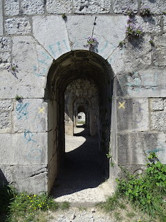 Arched stone entrance of Fort de la Bastille with weathered walls and dark passageway leading through