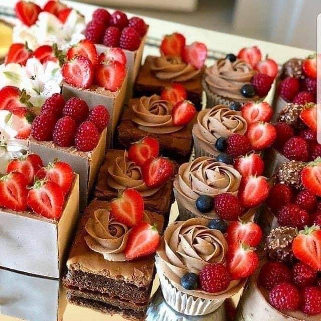 Assorted fruit tarts with strawberries, raspberries, and chocolate cream in square and round shapes