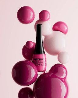 Pink nail polish bottle floating among shiny pink and white bubles on a pink background
