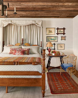 Rustic bedroom with antique four-poster bed, wood ceiling beams, curtained window, and vintage decor
