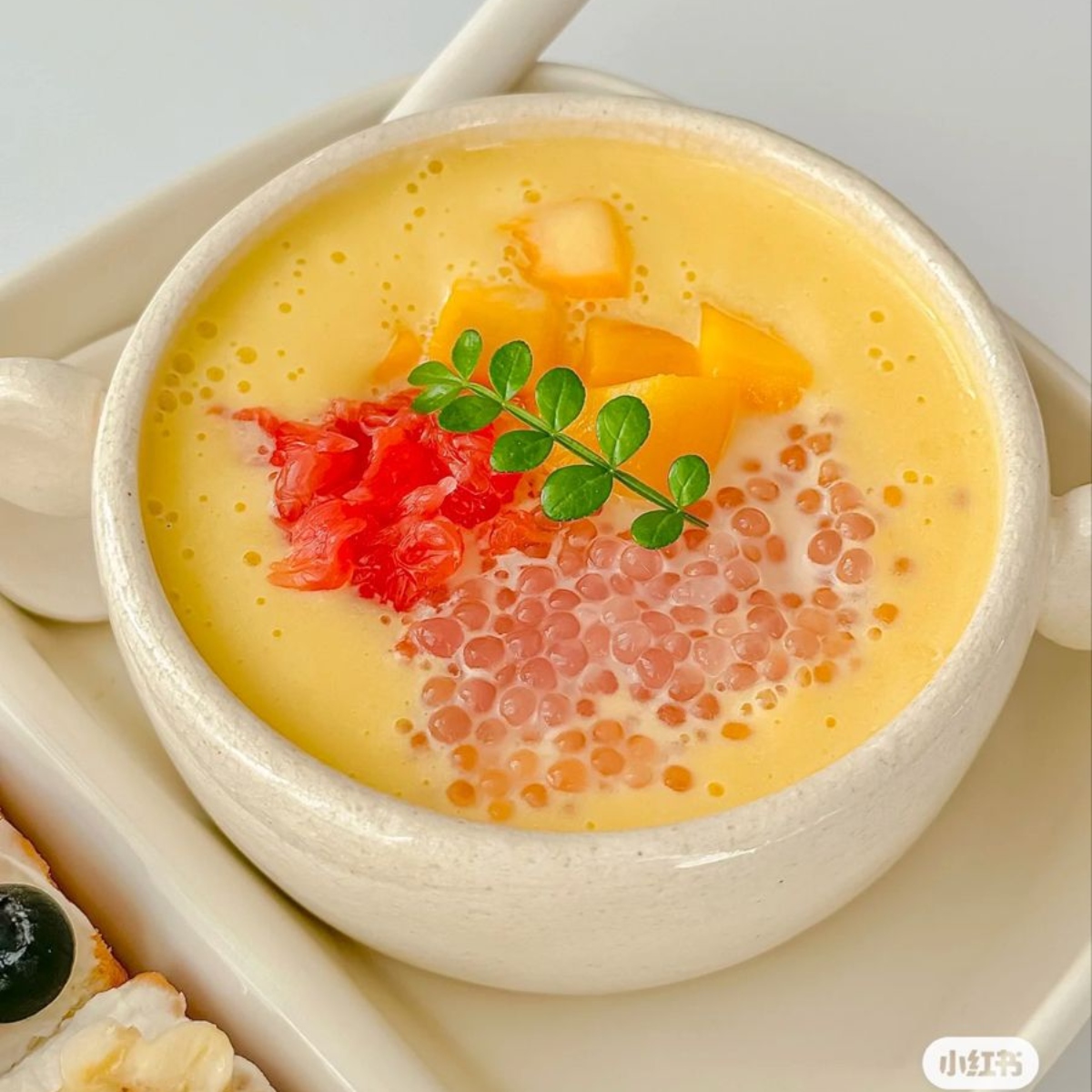 Bowl of mango pomelo sago with fruit toppings and tapioca pearls in creamy yellow base