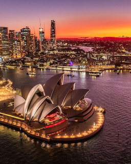 Sydney Opera House at sunset with harbor water and city skyline in the background