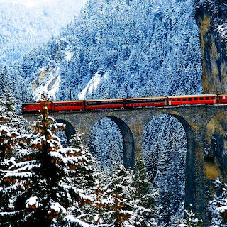 Red Train on Snowy Mountain Bridge