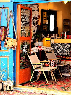Colorful shop interior with blue door, chairs, rugs, and decorative items on display