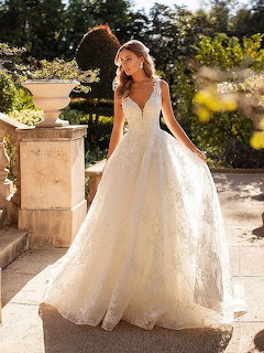 Woman wearing a white lace ball gown wedding dress standing in a garden pathway