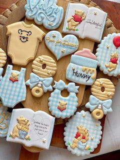 Assorted decorated baby shower cookies with Winnie the Pooh theme in blue and cream colors