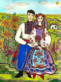 Couple in colorful Ukrainian folk costumes with embroidered details in rural setting with sunflowers