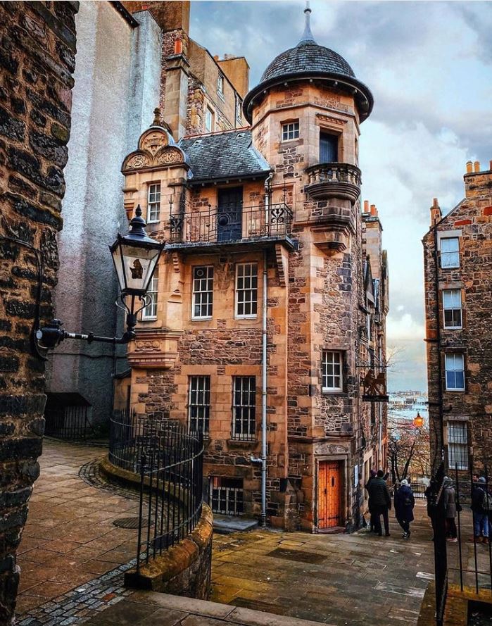Historic stone building with turret and dome in Edinburgh, Scotland under cloudy sky