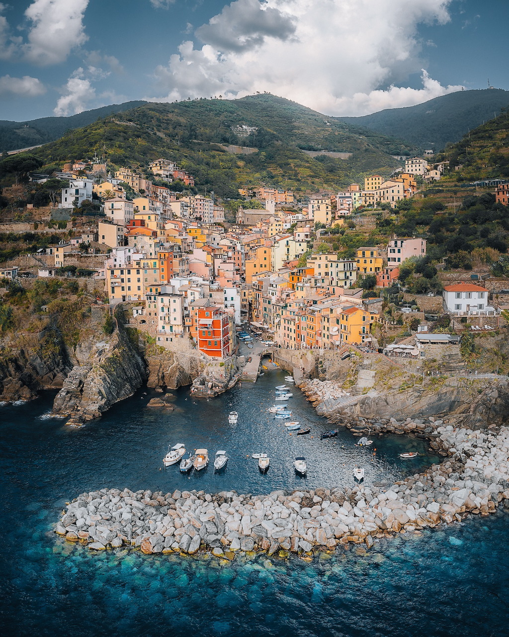 Colorful buildings of Riomaggiore village on a cliff above a small boat harbor in Cinque Terre, Italy