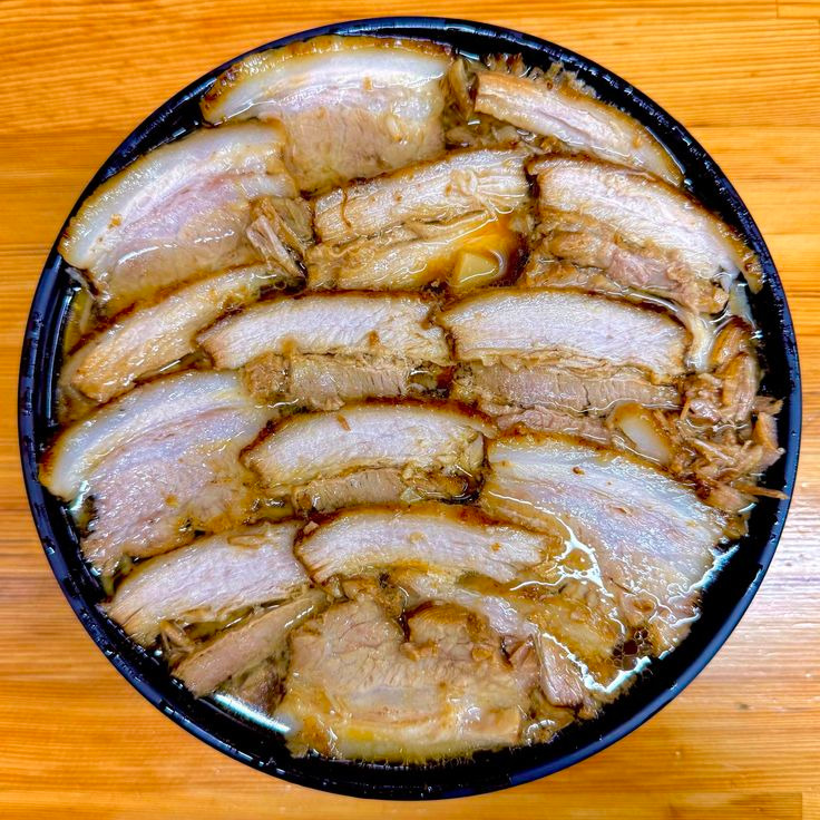Top-down bowl of char siu ramen with many slices of braised pork in broth