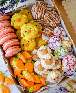 Box of assorted decorated spring cookies with chicks, carrots, lambs, macarons, and crinkle cookies