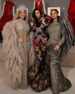 Three women in extravagant gowns posing together at a glamorous event