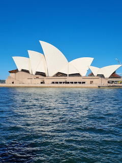 Sydney Opera House white shell roof structure on harbor waterfront under blue sky