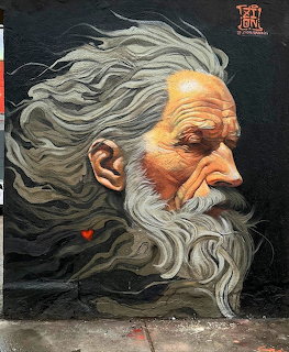 Street art mural of elderly man with long white hair and beard in profile on dark wall