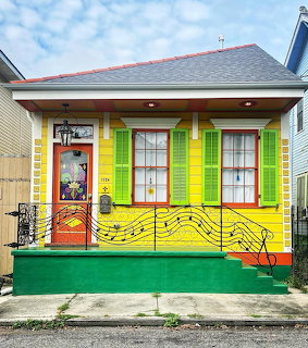Bright yellow house with green trim and painted musical notes on the facade